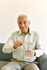Drinking water is good healthy habit for old man, Elderly smiling asian man pointing at glass of purified water, Senior healthcare concept.