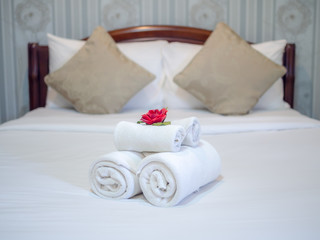 Fototapeta na wymiar White towels decoration with red flower on white clean bed in hotel room.