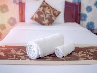 White clean towels on white clean bed in hotel room.