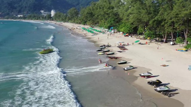 A jetski is driving fast to the beach of patong in phuket and stops in the sand.