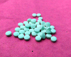 white medicine tablets on pink background