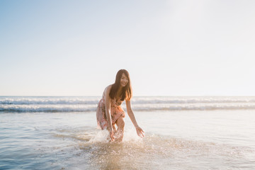 Young Asian woman walking on beach. Beautiful female happy relax walking on beach near sea when sunset in evening. Lifestyle women travel on beach concept.
