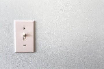 A white light switch on a grey wall