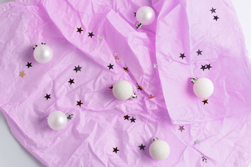 pink pastel background. Christmas balls, pompons and glitter stars. simple flat lay composition