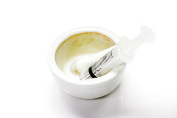 White liquid drug in a white ceramic cup and plastic syringe for injection to the patient isolate on white background.