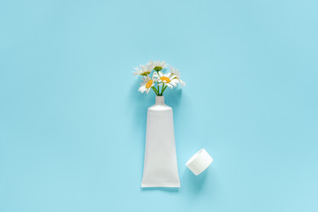 Bouquet of chamomile flowers from cosmetic, medical white tube for cream, ointment, toothpaste or other product. Concept natural herbal organic cosmetics, homeopathic cosmetology Mockup Copy space