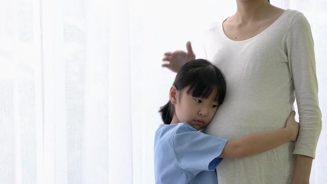 Asian family daughter hug and listening sound flex in pregnant mother belly. Children flex in the stomach. Concept of family, hope and new born.