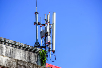Devices and Receivers Communication Signal with antennas on the top of building and bright blue sky...