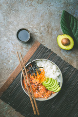 Hawaiian salmon poke bowl with seaweed, avocado, carrot, sesame seeds and rice. Top view, overhead, flat lay
