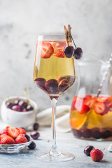 White wine sangria or punch with berries and ice in glass and pincher. Homemade refreshing fruit sangria.