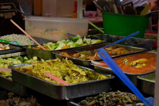 Recipientes met&aacute;licos rectangulares de acero inoxidable tipo buffete con diversos alimentos en mercado t&iacute;pico de m&eacute;xico, para servir comida corrida de inmediato a los clientes