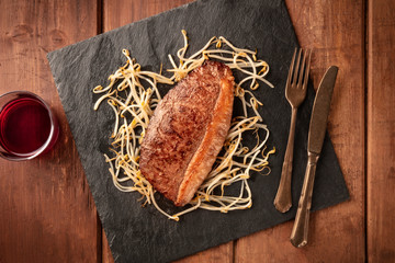 Kobe meat, wagyu beef steak, cooked, shot from above with soy sprouts and red wine