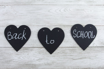Back to school text on heart shaped blackboard pieces on white wooden desk. Chalk, wood background. Education, September, school concept