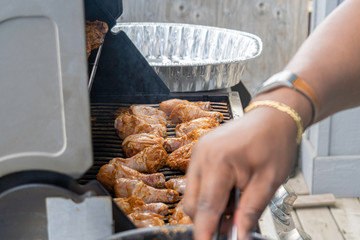 African American Nigerian man grilling roasting chicken thighs on Barbeque