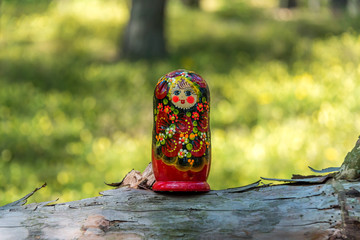 Russian Nesting Doll on a Log in a Forest on a Sunny Day