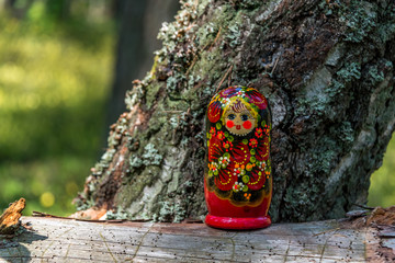 Russian Nesting Doll on a Log in a Forest on a Sunny Day
