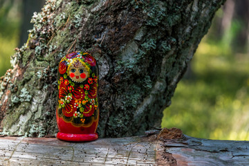 Russian Nesting Doll on a Log in a Forest on a Sunny Day