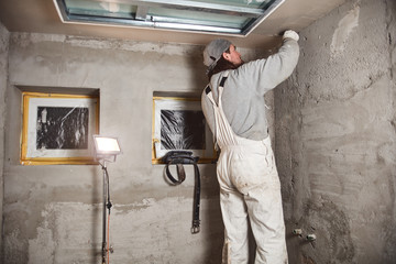 Construction worker plastering gypsum walls inside the house.