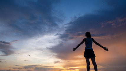 Silhouette of free woman enjoying freedom feeling happy at sunset. Serene relaxing woman in pure happiness