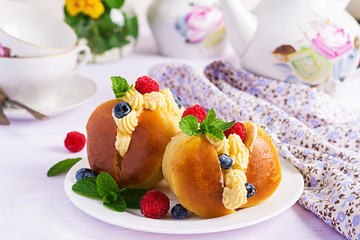 Rum baba decorated with whipped cream and fresh raspberry, blueberry. Savarin with rum, cream and berries. Italian cuisine