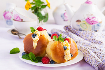 Rum baba decorated with whipped cream and fresh raspberry, blueberry. Savarin with rum, cream and...