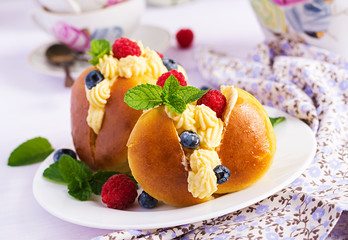 Rum baba decorated with whipped cream and fresh raspberry, blueberry. Savarin with rum, cream and berries. Italian cuisine