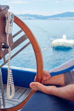 Sailor using wheel to steer rudder on a sailing boat.