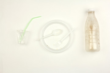 used dirty white plastic disposable tableware, plate fork spoon bottle cup and straw, on white background, dirty dishes after party, pollution and environmental problem