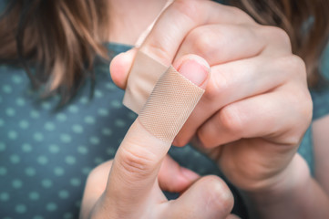 Woman puts a plaster on her injured finger