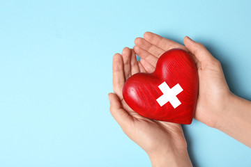 Woman holding heart on blue background, top view with space for text. Donation concept
