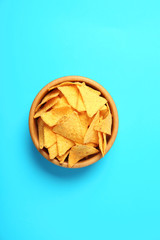 Tasty mexican nachos chips in wooden bowl on blue background, top view