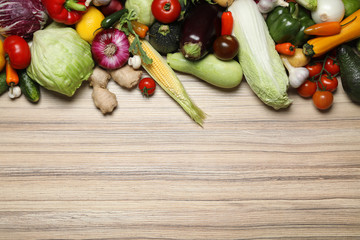 Different fresh vegetables on wooden table, flat lay. Space for text