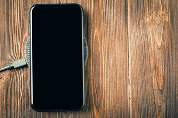 Charge your smartphone on the charging pad. Wireless charging on wooden table. rendered image.
