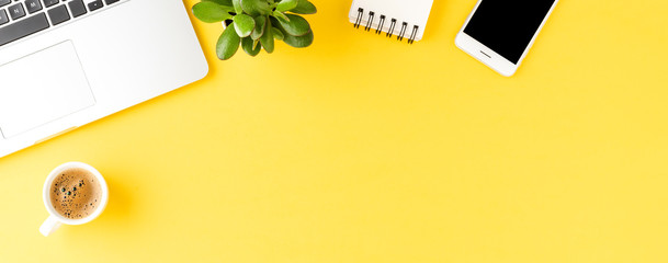 Office desktop with laptop and accessories on yellow background. Banner