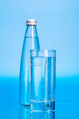 Glass water bottles on a light blue background