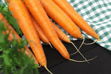 Fresh carrots on checkered tablecloth close up