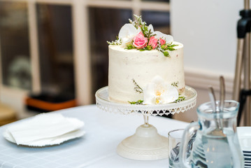 Obraz na płótnie Canvas White cream wedding cake with flower decoration on it.