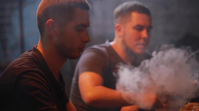Men friends smoking hookah playing backgammon in a bar