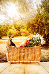 Wooden table background and autumn orchard view in distance. Flowers in baskets and some decoration on the table top. 