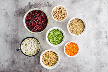 Variety of dry legume seeds in bowls: beans, lentils, peas, chickpeas, top view