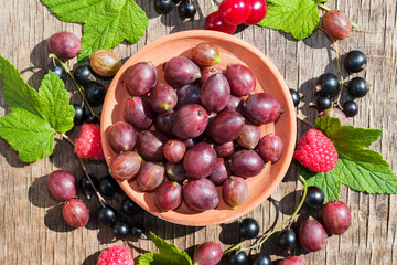 Plate with fresh ripe brown gooseberries on an old wooden table close-up