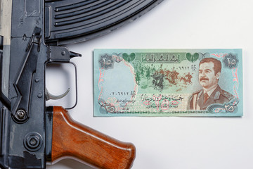 old Iraqi money depicting Saddam Hussein along with the Soviet AK 47