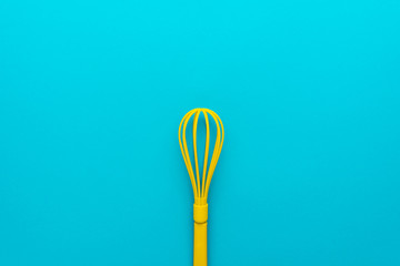 Top view photo of vivid plastic kitchen utensil. Minimalist flat lay image of yellow whisk over...