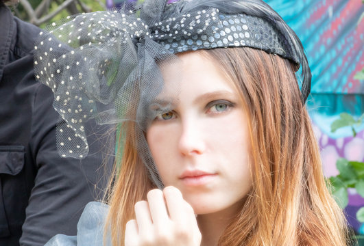  Jeune femme aux yeux vairons et pairs, dans une tenue tr&egrave;s &eacute;l&eacute;gante &agrave; un pique-nique vintage boho chic, belle &eacute;poque avec un chapeau bibi &agrave; voilette, steampunk