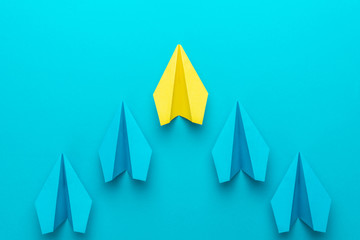 Leadership concept with paper planes over turquoise blue background with copy space. Top view of yellow plane leading blue ones. Flat lay image of business competition concept.