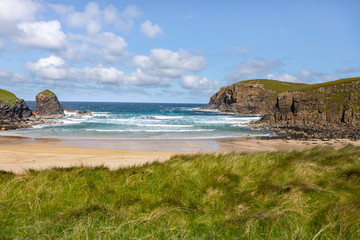 sandy bay with waves crashing onshore on the Isle of Lewis, Outer Hebrides in Scotland on a sunny day