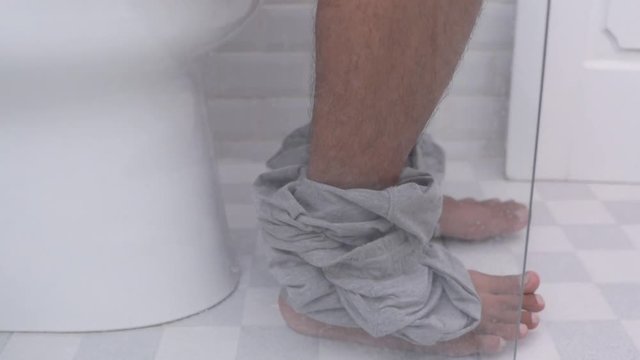 concept of a man sit on toilet and drop his pants down and pooping