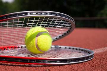 Tennis ball resting on top of a tennis racquet