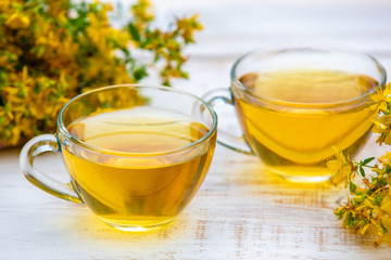 Two cups of Hypericum herbal (Tutsan) tea on wooden grunge table