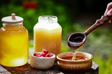 fresh sweet honey dripping in a wooden spoon in a ceramic bowl